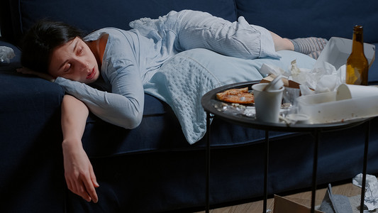 疲倦摄影照片_抑郁的女人独自躺在沙发上，感到疲倦、脆弱、虚弱的哭泣