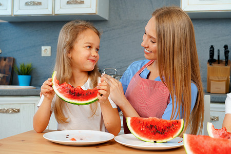 吃女孩西瓜摄影照片_妈妈和女儿在家吃西瓜