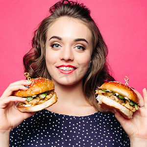 积极的女孩微笑着和两个美味的汉堡包合影。