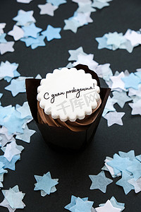 生日快乐用俄语写在美味的巧克力蛋糕上，深色背景上有奶油。