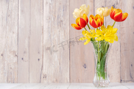 玻璃花瓶中的郁金香插花，心语问候，木桌背景墙上的喷壶装饰，特写，母亲节设计理念。