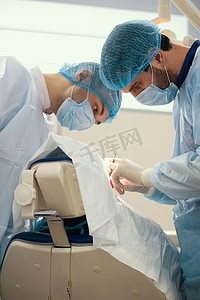 蓝色长袍的两位外科医生在手术室做手术