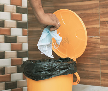手将医用面罩扔进封闭的垃圾箱 — Covid-19，Coronavirus 建议在使用后丢弃或将医用面罩扔进封闭的垃圾桶 — 表明要进行卫生实践的概念。