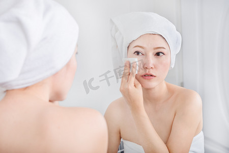 女人照镜子，用棉花擦脸