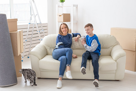 满足快乐的白人母亲和儿子在乔迁派对期间与他们的苏格兰折耳猫愉快地交流讨论新公寓的设计。