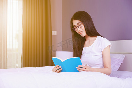 在家卧室床上看书的女人