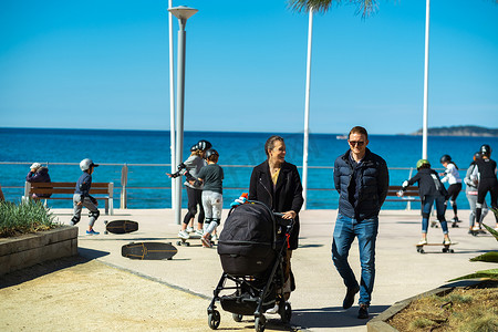 2019年4月5日。法国滨海圣西尔。村堤上有婴儿车的幸福家庭和玩滑板的孩子