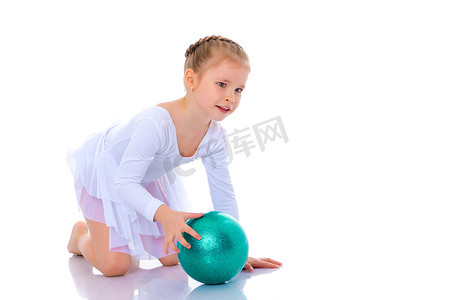 的小女孩在健身的大球上锻炼。