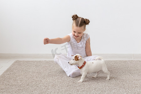 宠物、童年和动物概念 — 小女孩和小狗杰克罗素梗在地板上玩耍