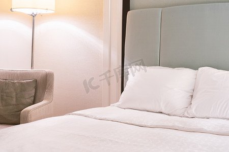 酒店沙发摄影照片_干净舒适的现代酒店卧室内饰，带立灯的暖色调房间，带垫子的亚麻沙发，豪华旅行的设计理念，特写。
