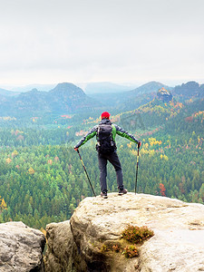绿色杆子摄影照片_山顶上的导游手拿杆子，背着沉重的背包。