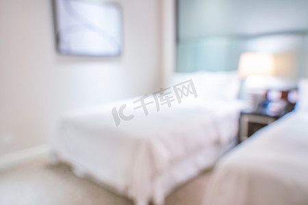 干净舒适的现代酒店卧室内部配有双人床，抽象的散焦模糊与散景背景，豪华旅行的设计理念。