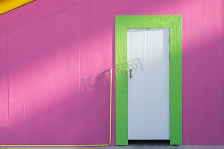 阳光下的绿色木门和粉色墙壁