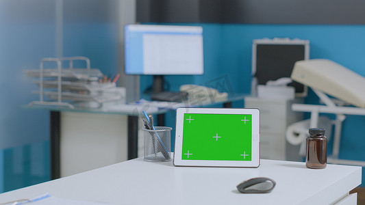 在空荡荡的医院办公室的桌子上放置着带有独立显示屏的模拟绿屏平板电脑