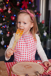 小女孩在厨房里吃生姜饼干的面团