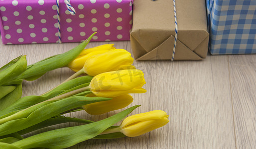 春天的郁金香花和木桌上的礼品盒。