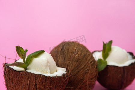粉红色背景中用薄荷叶装饰的新鲜椰子半香草冰淇淋球