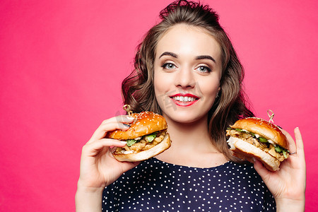 积极的女孩微笑着和两个美味的汉堡包合影。