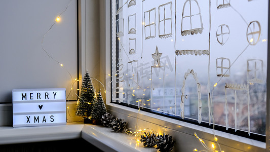 窗台上带有文字“圣诞快乐”的灯箱。