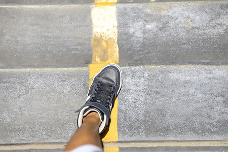 穿着长运动鞋的男人腿带着黄色走下公共楼梯