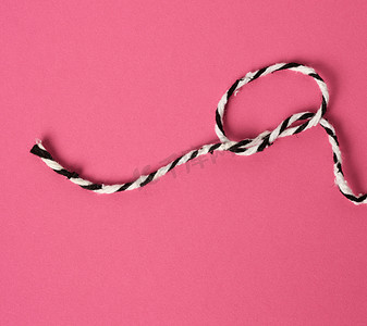 粉红色背景上的白黑绳子扭成一个环