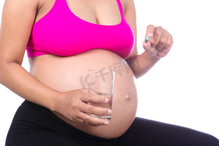 孕妇生病摄影照片_孕妇手的特写，背景是一杯水和药丸