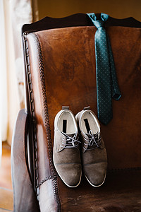 衣柜木质摄影照片_新郎的鞋子和圆点领带系在房间的皮椅上。
