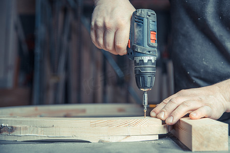 电动工具工具摄影照片_使用电钻头在细木工中拧紧木制家具