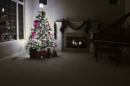 夜间客厅摄影照片_装饰精美的圣诞树被发光的火焰照亮
