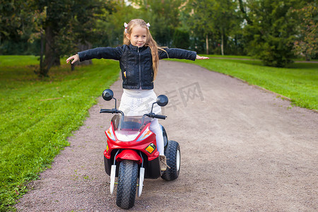 阳光开心摄影照片_可爱的小女孩在她的玩具摩托车上玩得很开心