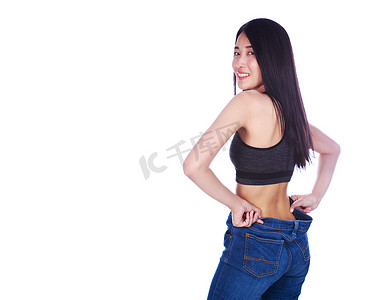 减肥成功摄影照片_女人展示了她的减肥效果，穿着白色背景中突显的旧牛仔裤