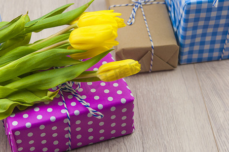 春天的郁金香花和木桌上的礼品盒。