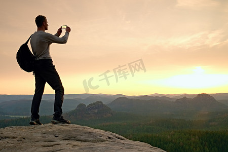 运动员在山顶用手机拍照。