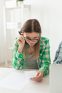 心烦意乱的年轻女性通过将信息输入笔记本电脑进行家庭记账，来考虑购买和支付信贷的费用金额。