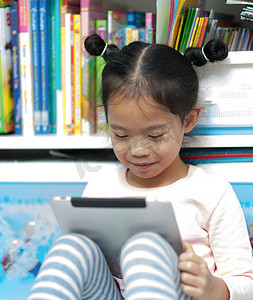 亚洲泰国摄影照片_亚洲泰国女孩儿童孩子坐着看书自我快乐阅读平板电脑