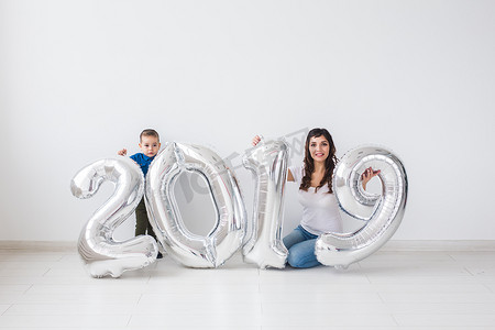 2019年快乐摄影照片_新的 2019 年即将到来的概念-快乐的母亲和小儿子在室内有银色数字。