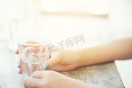 水里的手摄影照片_玻璃杯里的水，女人的手和咖啡店桌子上的瓶子