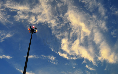 城市电力摄影照片_城市电力聚光灯柱，多云蓝色 Sk 上的剪影