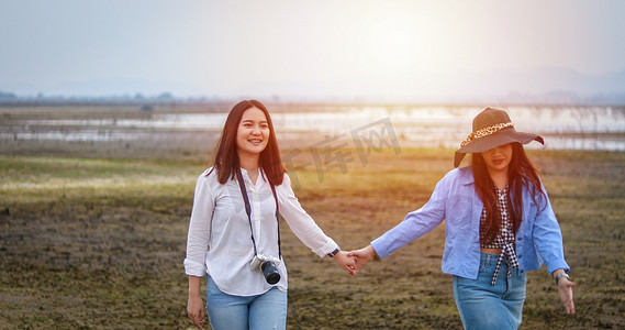 晚上，亚洲年轻女性在绿色的田野上玩得开心，笑着拥抱。