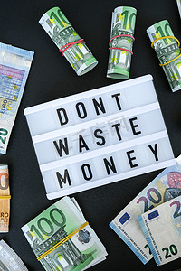 省心省力省钱摄影照片_在欧元纸币周围用黑色字母写着“不要浪费钱”的灯箱板。