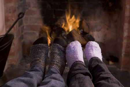 夫妇的脚在壁炉旁取暖