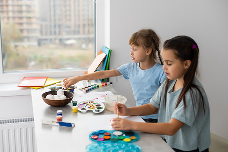 桌边的两个小女孩拿着画画的颜料