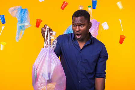 垃圾、塑料回收、污染和环境概念问题 — 黄色背景中提着垃圾袋的惊讶男子