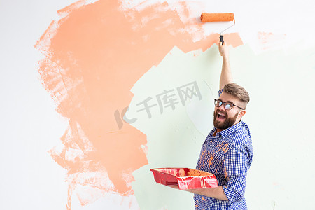 粉刷滚筒摄影照片_男性用油漆滚筒粉刷墙壁。