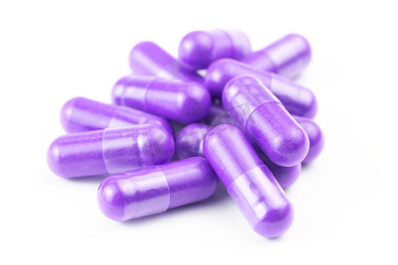 一堆质子紫色有机胶囊分离在白色背景特写与选择性聚焦