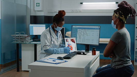 戴面罩的医生指着带有心形图案的平板电脑
