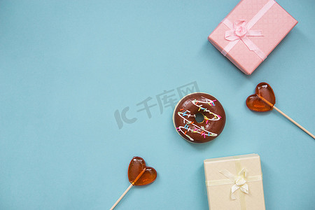 蓝色背景上的红心、礼物和贺卡形式的棒棒糖。
