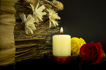 玫瑰花黑色摄影照片_在花中燃烧的黄色蜡烛火焰