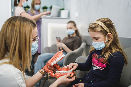 牙医向孩子病人展示牙齿模型
