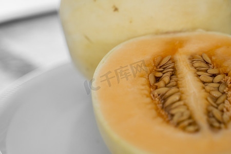 白盘上的新鲜甜橙瓜作为背景，有选择性地聚焦。